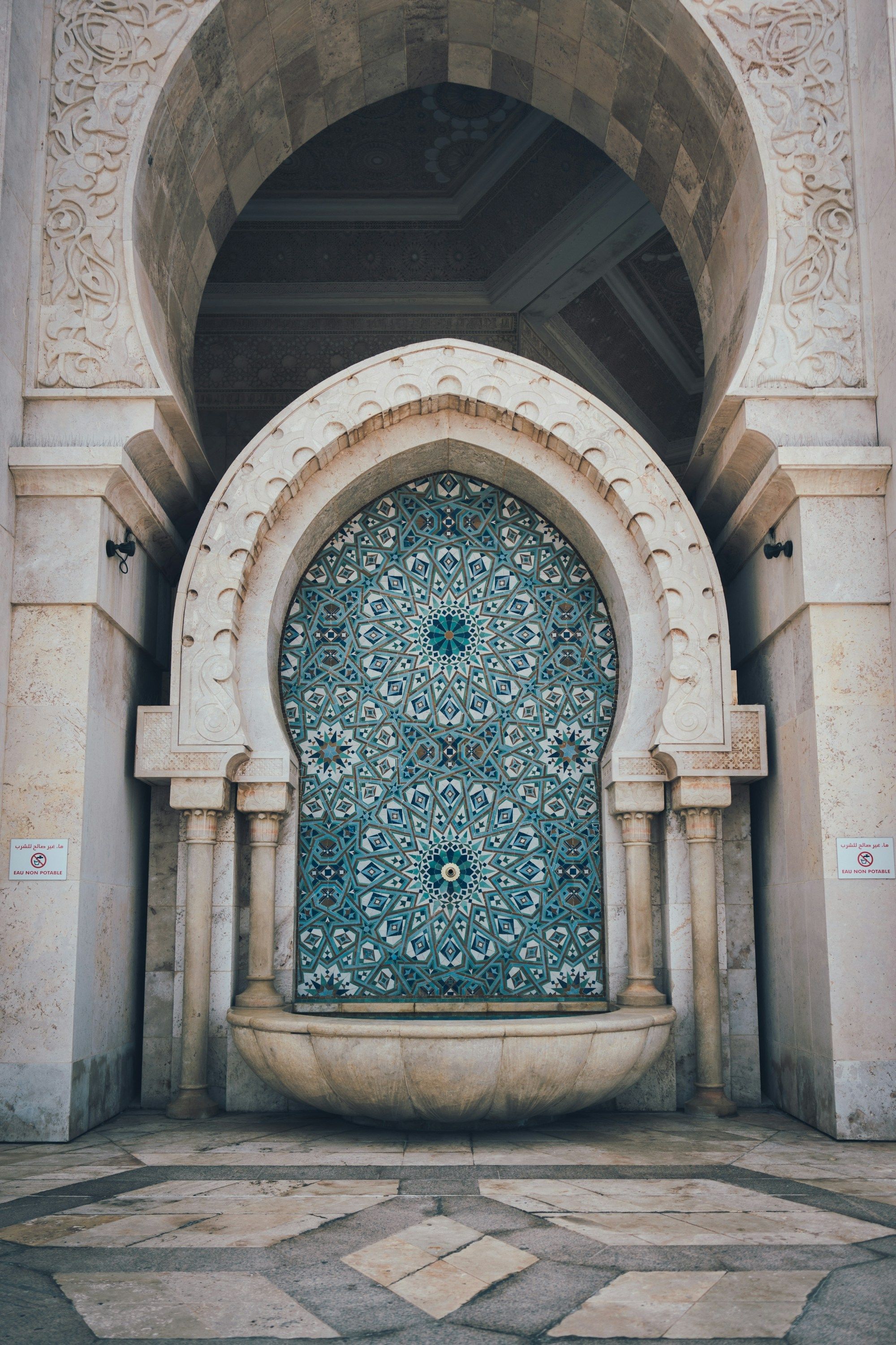 Brunnen mit traditionellen marokkanischen Zellige-Fliesen in einem Hufeisenbogen